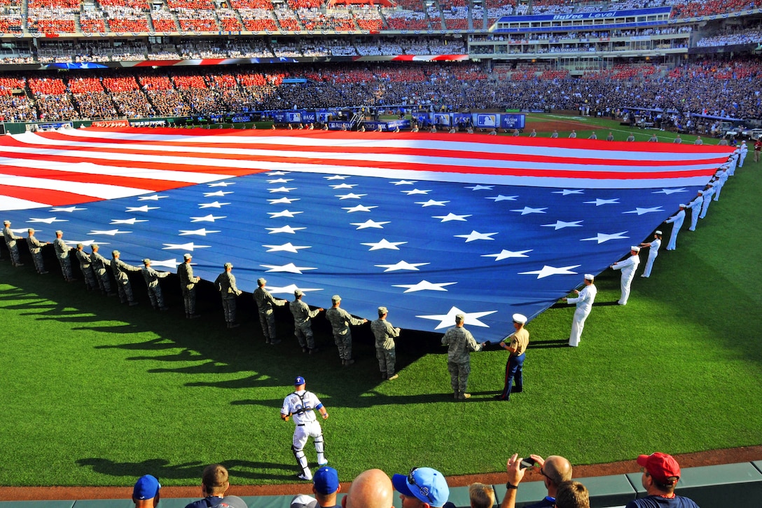 Sailors and airmen present a giant American flag before the 2012 major league baseball All-Star Game in Kansas City, Mo., July 10, 2012. The sailors are assigned to Navy Recruiting District Saint Louis and the Navy Operational Support Center, Kansas City, and the airmen are assigned to Whiteman Air Force Base, Mo. More than 30 sailors and 45 airman held the flag during the singing of the national anthem and pregame events.  
