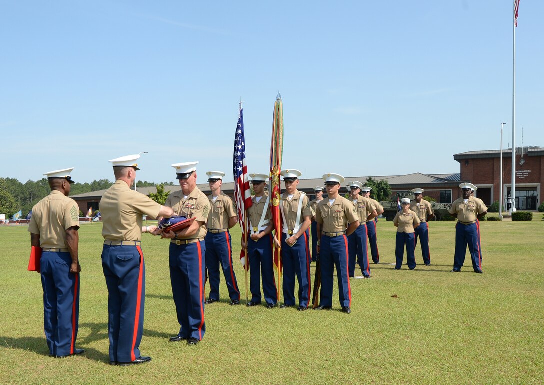 Sgt. Maj. Conrad Potts, outgoing sergeant major, Marine Corps Logistics Base Albany, receives an American flag flown in his honor over Coffman Hall from Col. Don Davis, commanding officer, MCLB Albany, during a retirement ceremony at Schmid Field, May 23.