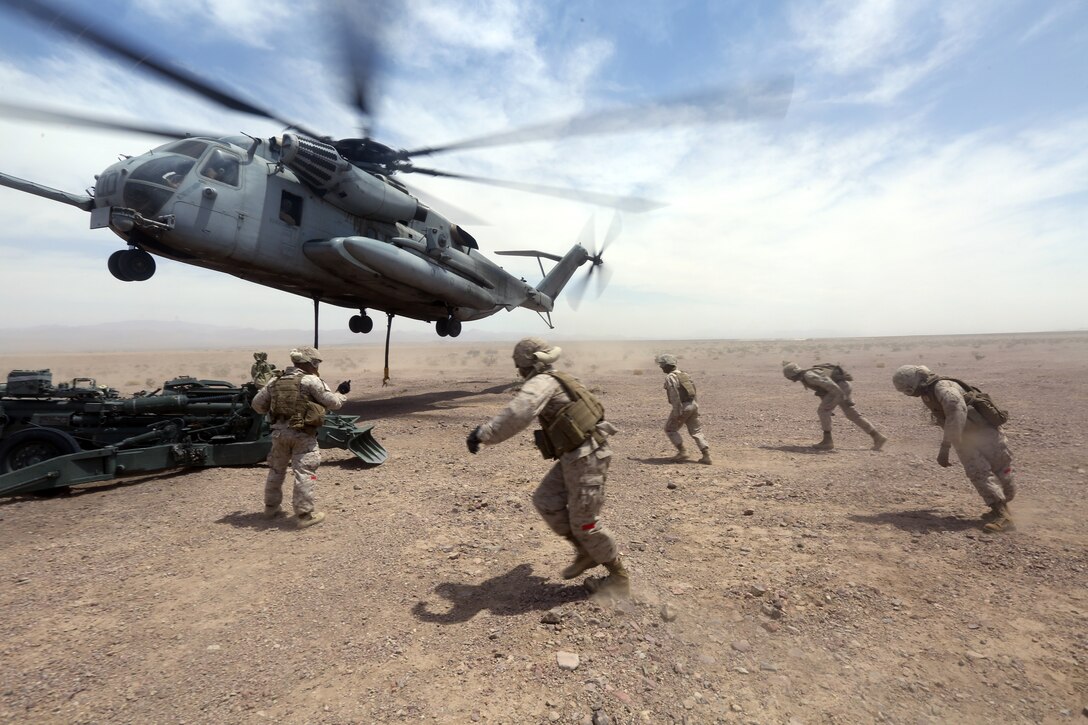 Marines with Combat Logistics Battalion 1 run to a M777A2 lightweight howitzer while a Ch-53 super stallion helicopter hovers above during Exercise Desert Scimitar at Marine Corps Air Ground Combat Center Twentynine Palms, Calif., May 8 2014. Desert Scimitar is a two-week, combined-element exercise to prepare Marines for deployments.  The Ch-53 is able to transport a howitzer quickly to locations that would otherwise be inaccessible. (U.S. Marine Corps photo by Lance Cpl. Ashton Buckingham)