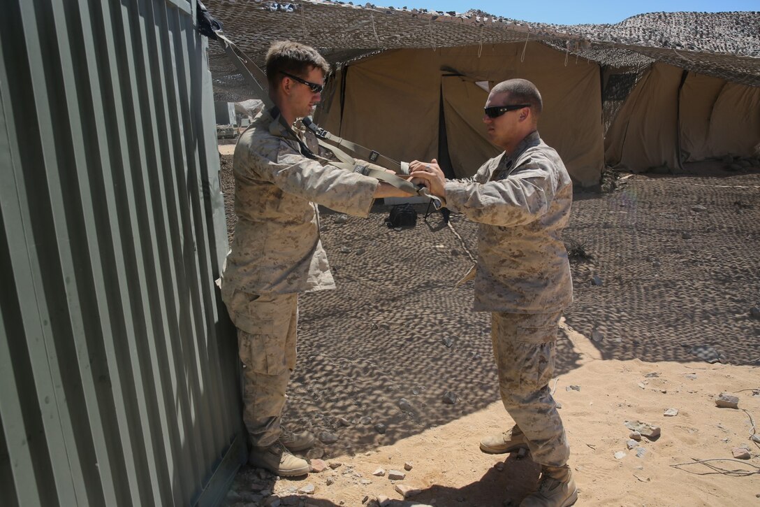 Petty Officer 2nd Class Daniel Wagner, left, a hospital corpsman with Headquarters Battalion, 1st Marine Division, monitors Lance Cpl. Aaron Brown, a motor transport operator with the battalion, during a physical therapy session at Marine Corps Air Ground Combat Center Twentynine Palms, Calif., May 14, 2014. Wagner routinely improvises medical treatment while in the field. He understands the work tempo of the Marines requires the battalion aid station to be creative when continuing treatment for their patients.