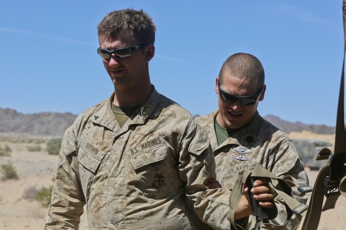 Petty Officer 2nd Class Daniel Wagner, right, a hospital corpsman with Headquarters Battalion, 1st Marine Division, instructs Lance Cpl. Aaron Brown, a motor transport operator with the battalion, during a physical therapy session at Marine Corps Air Ground Combat Center Twentynine Palms, Calif., May 14, 2014. The battalion is in the middle of Exercise Desert Scimitar, a I Marine Expeditionary Force live-fire exercise. Wagner, a native of Parker, Ariz., improvises in the field to help service members maintain and progress in their medical treatment. He developed resistance and stretching techniques with a piece of workout equipment to help Brown with his strained shoulder.