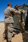 Petty Officer 2nd Class Daniel Wagner, left, a hospital corpsman with Headquarters Battalion, 1st Marine Division, spots Lance Cpl. Aaron Brown, a motor transport operator with the battalion, during a physical therapy session at Marine Corps Air Ground Combat Center Twentynine Palms, Calif., May 14, 2014. The battalion is in the middle of Exercise Desert Scimitar, a I Marine Expeditionary Force live-fire exercise. Wagner, a native of Parker, Ariz., improvises in the field to help service members maintain and progress in their medical treatment. He developed resistance and stretching techniques with a piece of workout equipment to help Brown with his strained shoulder.