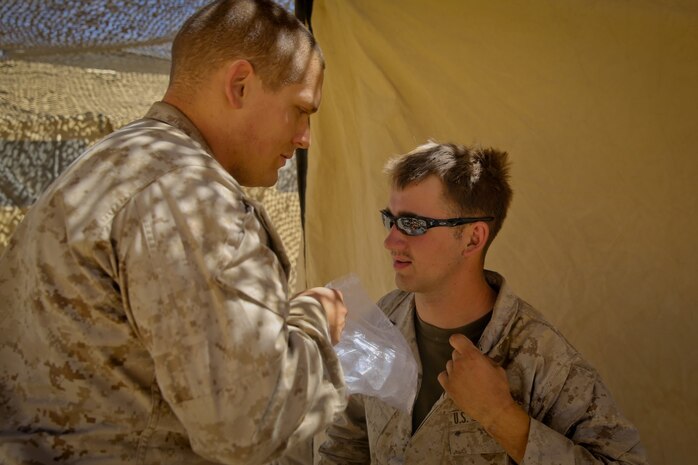 Petty Officer 2nd Class Daniel Wagner, left, a hospital corpsman with Headquarters Battalion, 1st Marine Division, sets an ice pack on the shoulder of Lance Cpl. Aaron Brown, a motor transport operator with the battalion, after a physical therapy session at Marine Corps Air Ground Combat Center Twentynine Palms, Calif., May 14, 2014. Wagner routinely improvises medical treatment while in the field. He understands the work tempo of the Marines requires the battalion aid station to be creative when continuing treatment for their patients.