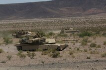Marines with Alpha Company, 1st Tank Battalion, advance in formation on a mock enemy position in an M1A1 abrams main battle tank during Exercise Desert Scimitar aboard Marine Corps Air Ground Combat Center Twentynine Palms, Calif., May 11, 2014. The training gave the Marines the opportunity to refine and rehearse essential combat skills needed in a battlefield environment. Desert Scimitar is an annual exercise that includes elements from the I Marine Expeditionary Force. The exercise focused on conventional operations and provided realistic training that prepared Marines for overseas operations. (U.S. Marine Corps photo by Cpl. Christopher J. Moore/Released)