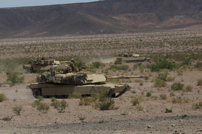 Marines with Alpha Company, 1st Tank Battalion, advance in formation on a mock enemy position in an M1A1 abrams main battle tank during Exercise Desert Scimitar aboard Marine Corps Air Ground Combat Center Twentynine Palms, Calif., May 11, 2014. The training gave the Marines the opportunity to refine and rehearse essential combat skills needed in a battlefield environment. Desert Scimitar is an annual exercise that includes elements from the I Marine Expeditionary Force. The exercise focused on conventional operations and provided realistic training that prepared Marines for overseas operations. (U.S. Marine Corps photo by Cpl. Christopher J. Moore/Released)
