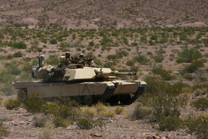 Marines with Alpha Company, 1st Tank Battalion, advance in formation on a mock enemy position in an M1A1 Abrams main battle tank during Exercise Desert Scimitar aboard Marine Corps Air Ground Combat Center Twentynine Palms, Calif., May 11, 2014. The training gave the Marines the opportunity to refine and rehearse essential combat skills needed in a battlefield environment. Desert Scimitar is an annual exercise that includes elements from the I Marine Expeditionary Force. The exercise focused on conventional operations and provided realistic training that prepared Marines for overseas operations. (U.S. Marine Corps photo by Cpl. Christopher J. Moore/Released)