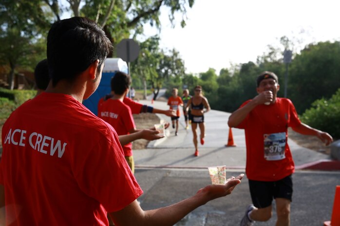 Members of the race crew hand water to competitors during the 16th annual City of Laguna Hills Memorial Day half marathon, 10k and 5k May 26, 2014. The race honored those who are currently serving, those who have served and those who have made the ultimate sacrifice. The event also raised awareness and support from the local community for 3rd Battalion, 5th Marine Regiment, or "Dark Horse Battalion," with a portion of the event proceeds going to the battalion's support committee.