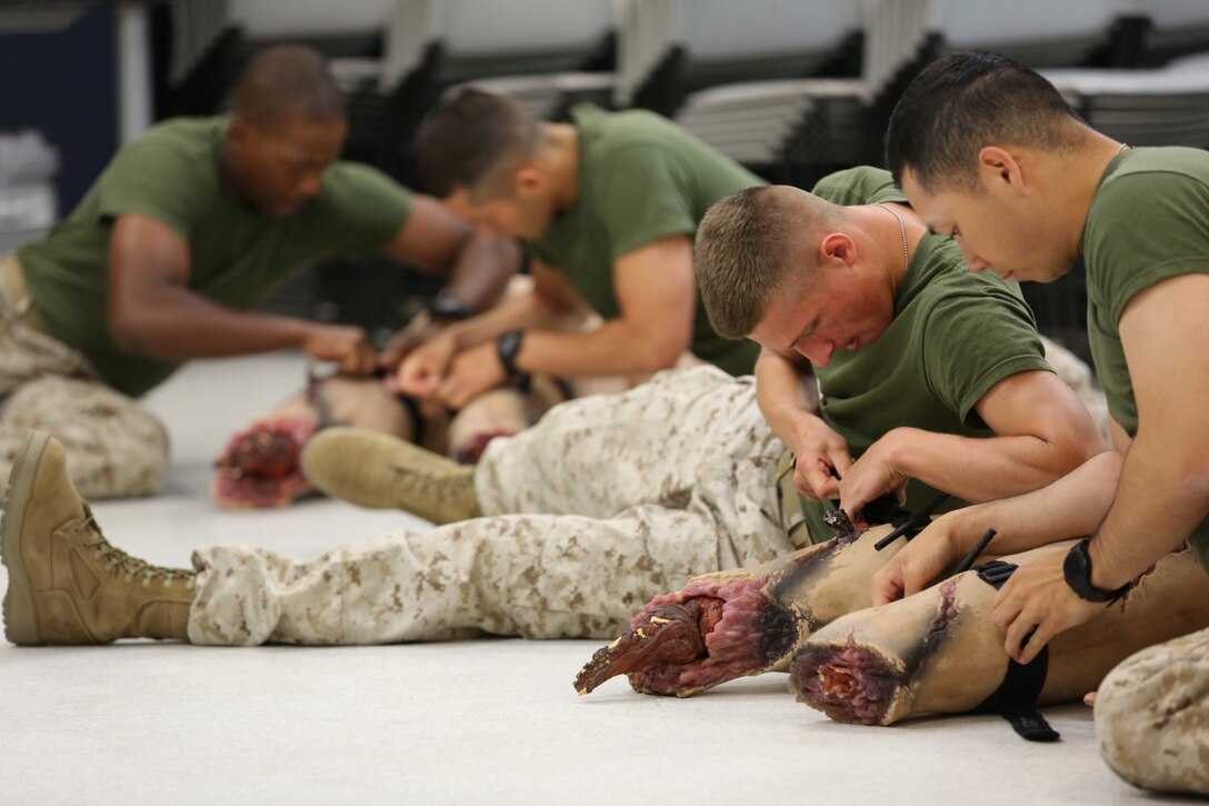 Corpsmen attending Field Medical Training Battalion West fasten tourniquets to double-amputee practice dummies during a practical exercise, May 23, 2014.  Marine Corps and Navy instructors from FMTB taught students the basics of hemorrhage control aboard Camp Pendleton, California.