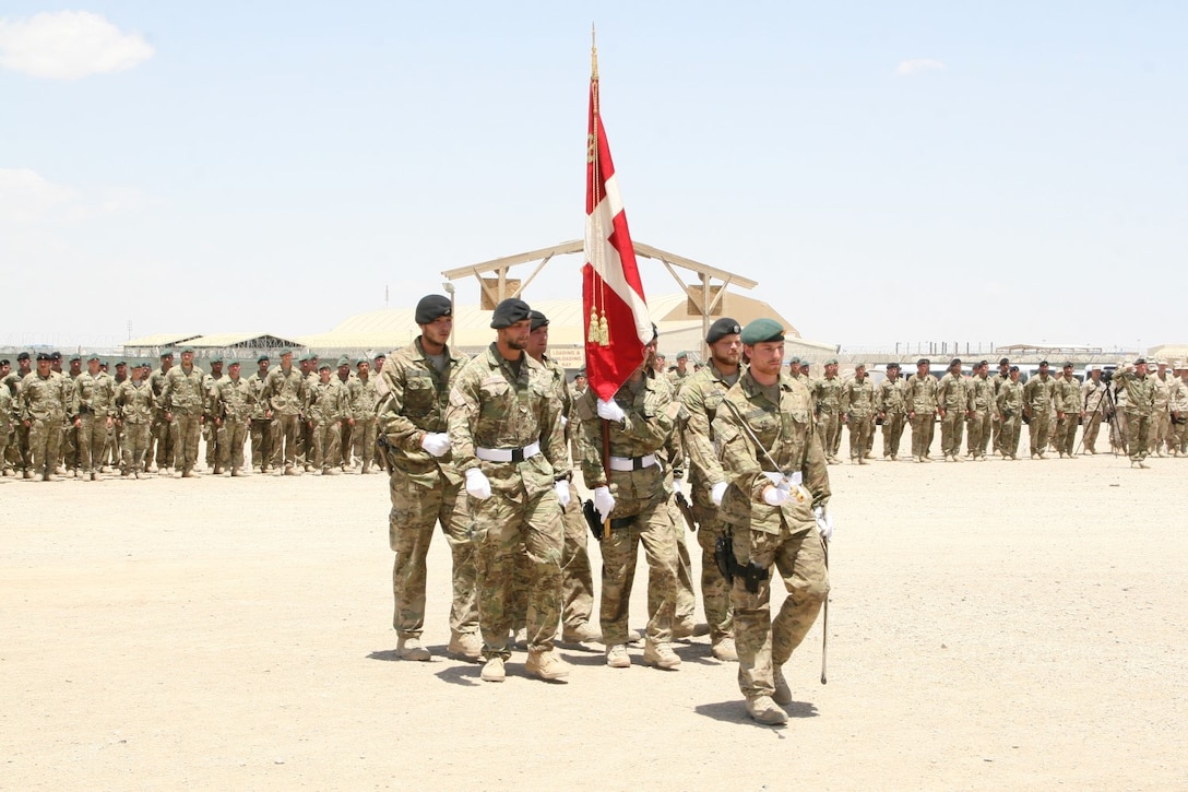 The Danish color guard marches the Denmark flag away to be packed for their journey home during their end of mission ceremony aboard Camp Bastion, Afghanistan, May 20, 2014. This symbolizes the Danish Contingent mission in Afghanistan has come to an end and their journey home has begun.