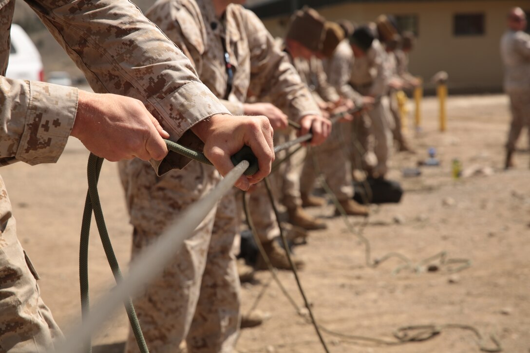 Marine Corps Mountain Warfare Training Center Marines finish their knots during the knot-tying portion of the Instructor Qualification Course at the lower base camp of MCMWTC, May 1, 2014. A line of rope was tied in two direction allowing for students to practice tying knots while instructors evaluated them.
