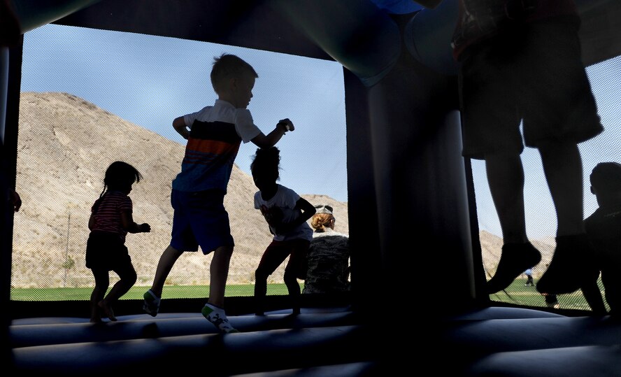Children jump and play in bounce houses during the 2014 Creech Summer Bash event at Lone Mountain Park May 19, 2014. The annual Creech Summer Bash and resiliency event provided water gun wars, bouncy houses, face painting, football, and more. (U.S. Air Force photo by Senior Master Sgt. C.R.)
