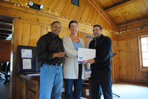 Grand Forks Air Force Base chaplains, Maj. Steven Dabbs and Capt. Ruben Covos, present Tanya Pavlik with a certificate and bronze lapel pin from the Office of the President of the United States recognizing her as a recipient of a bronze level Presidential Volunteer Service Award during a volunteer appreciation picnic held May 17, 2014, at Turtle River State Park, N.D. The bronze level award is presented to adults age 25 and older who have donated 100-249 volunteer hours in a 12-month period. Pavlick donated a total of 108 hours. (U.S. Air Force photo/Staff Sgt. Luis Loza Gutierrez)