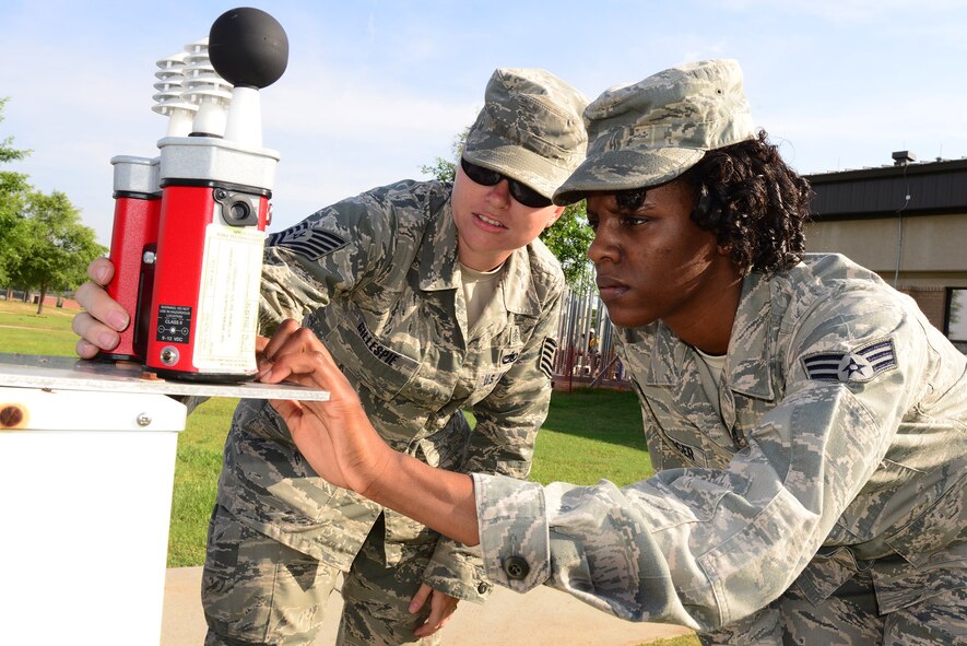 U.S. Air Force Tech. Sgt. Kristi Gillespie, left, 23d Aerospace Medical Squadron NCO in charge of occupational health, teaches U.S. Air Force Senior Airman Juawana Stringer, 23d AMDS bioenvironmental technician, how to use a Wet Bulb Globe Temperature (WBGT) device at Moody Air Force Base, Ga., May 29, 2014. The WBGT device measures thermal conditions to help bioenvironmental Airmen determine heat conditions which ensure outdoor workers follow proper work and rest cycles. (U.S. Air Force photo by Senior Airman Tiffany M. Grigg/Released) 