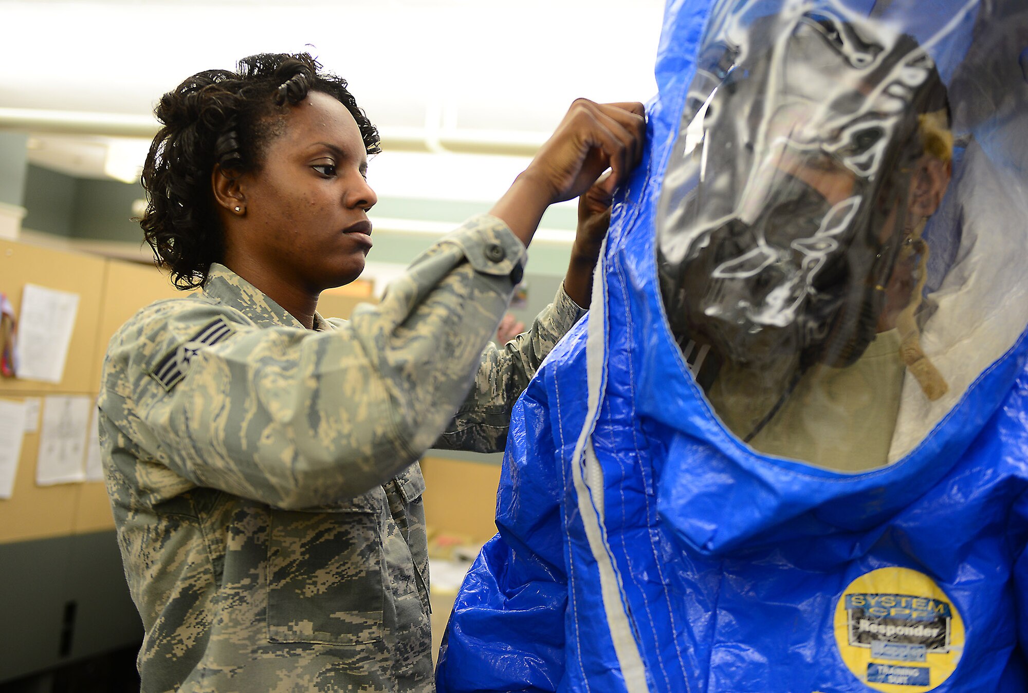 U.S. Air Force Senior Airman Juawana Stringer, 23d Aerospace Medicine Squadron bioenvironmental technician, assists U.S. Air Force Senior Airman Christopher Cameron, 23d AMDS bioenvironmental engineering technician, don a training Level A suit, at Moody Air Force Base, Ga., May 29, 2014. Bioenvironmental Airmen train with the suit twice per quarter, ranging from in house training to training with other emergency responders such as the fire department and emergency management. (U.S. Air Force photo by Senior Airman Tiffany M. Grigg/Released) 