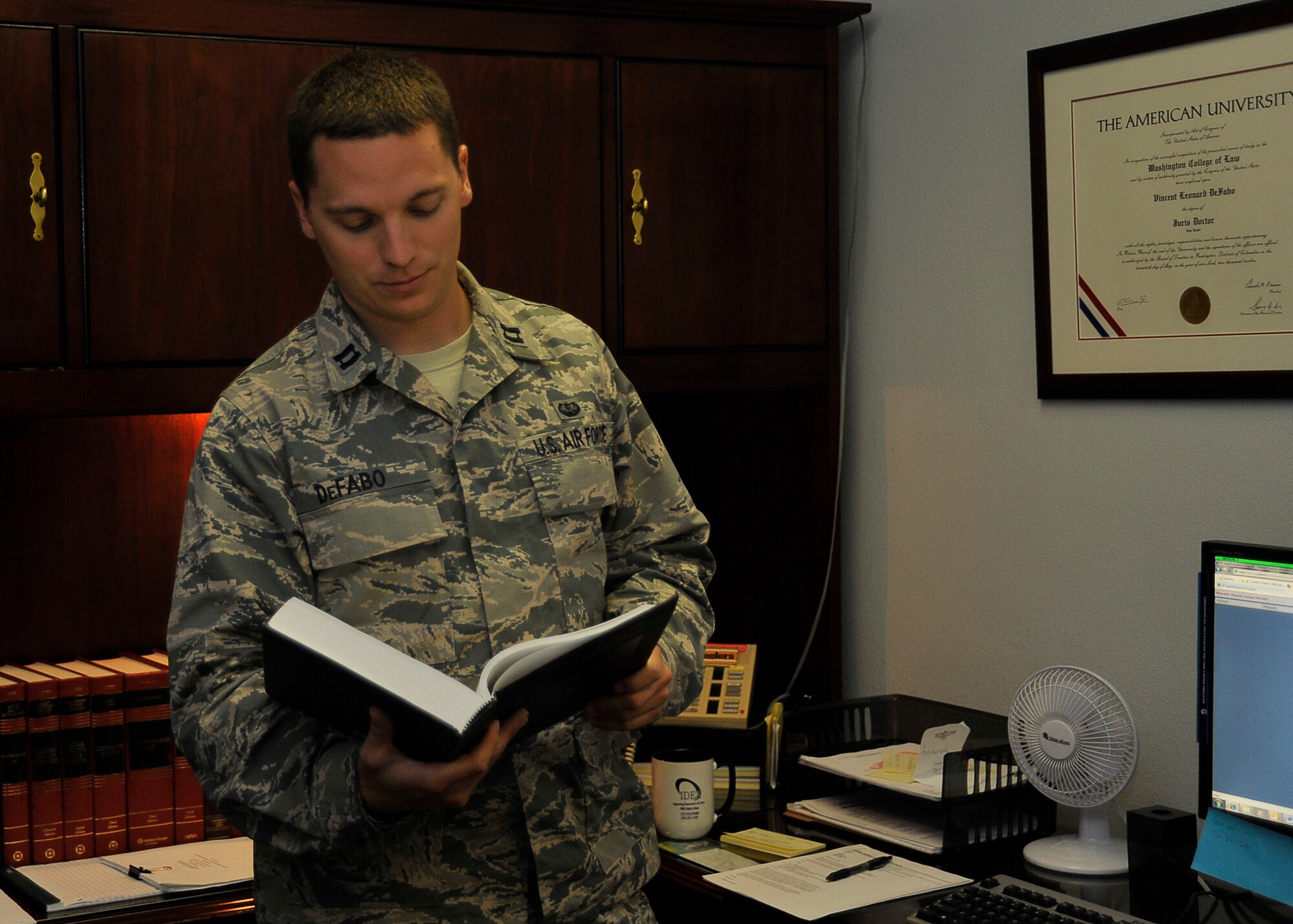 Capt. Vincent DeFabo, 325th Fighter Wing Judge Advocate chief of legal assistance and preventative law, refers to text for verification May 28 at the legal office. In the legal office judge advocates or attorneys assist Airmen, retirees and dependents with legal issues. (U.S. Air Force photo by Airman 1st Class Solomon Cook)