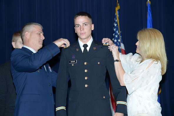 Col. Kyle 'Cowboy' Ingham and his wife Kira pin second lieutenant bars on their son Austin on May 20 at Joint Base-Randolph, Texas, as their son Houston looks on. (Air Force photo by Joel Martinez) 
