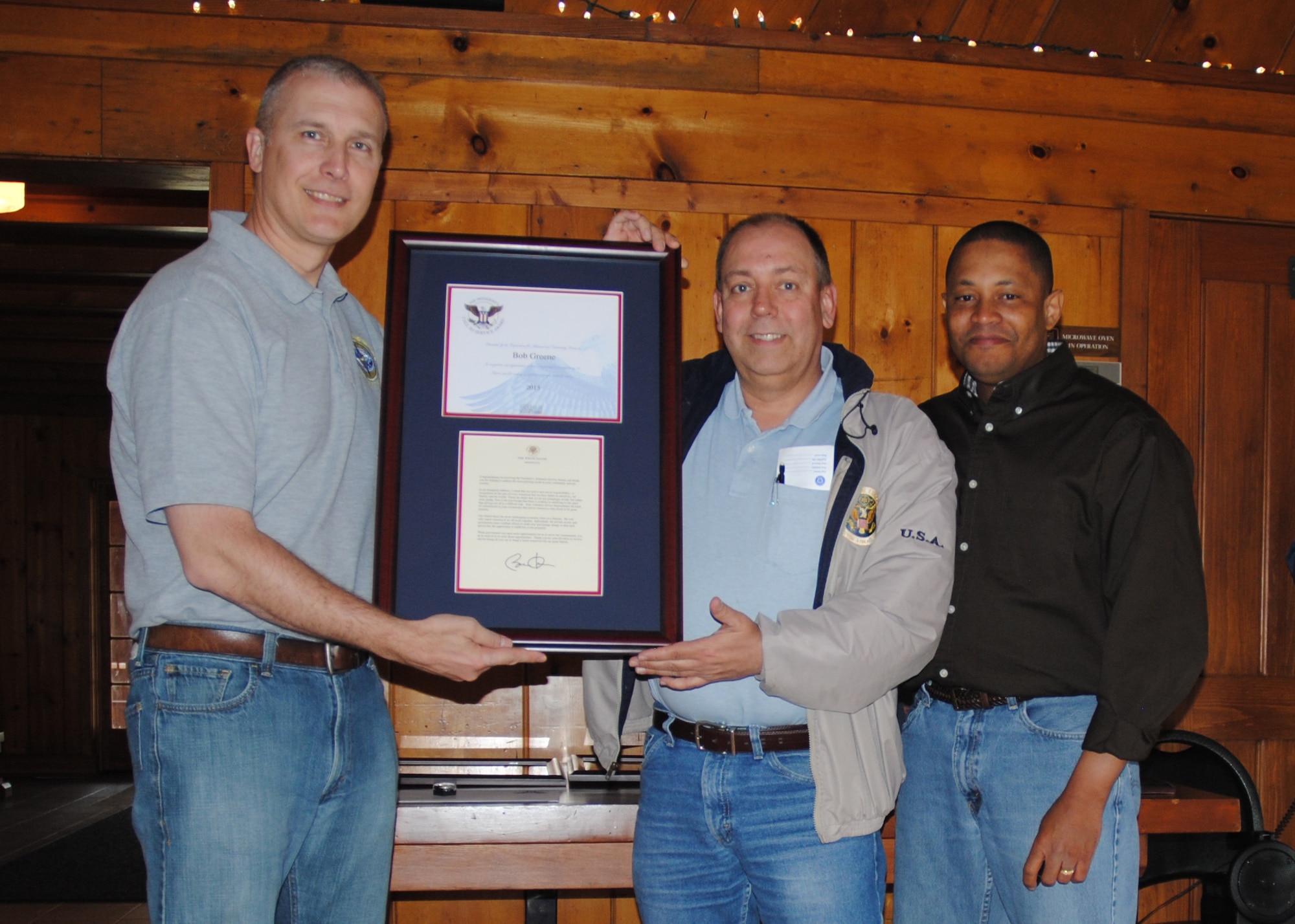 (At opposite ends from left) Col. Paul Bauman, 319th Air Base Wing commander and Chaplain (Maj.) Steven Dabbs, 319th ABW head chaplain, present Bob Greene with certificate and letter from the Office of the President of the United States recognizing him as a recipient of a Lifetime Presidential Volunteer Service Award during a volunteer appreciation picnic held May 17, 2014, at Turtle River State Park, N.D. The Lifetime Award is the highest recognition in the PVSA program. It is awarded to a person who has donated 4,000 volunteer hours or more over a lifetime. Greene generously donated a total of 4,931 hours. (U.S. Air Force photo/Staff Sgt. Luis Loza Gutierrez)