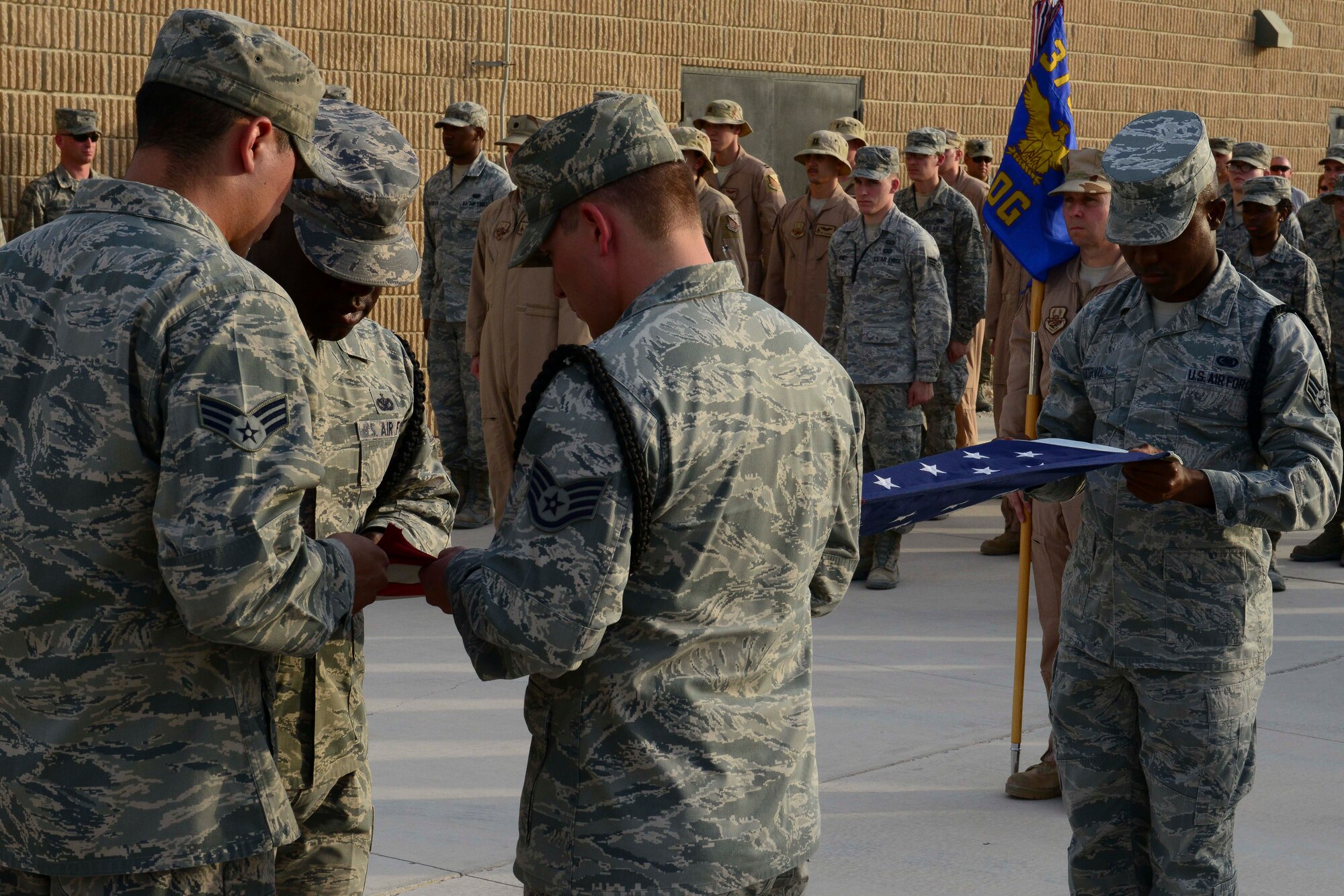 U.S. Air Force Airmen assigned to the 379th Air Expeditionary Wing honor guard fold the American flag during a retreat ceremony at Al Udeid Air Base, Qatar, May 26, 2014. The wing hosted Memorial Day events that included a 10K run, musical performances and a retreat ceremony. (U.S. Air Force photo by Staff Sgt. Ciara Wymbs)