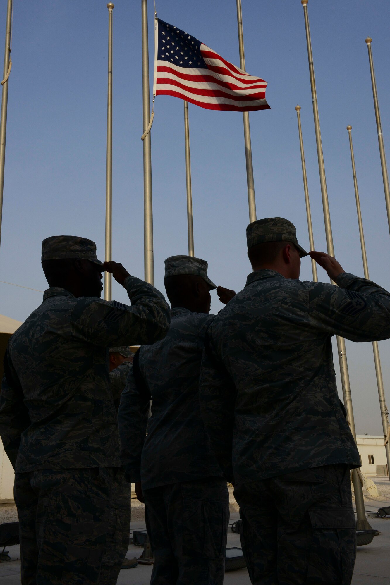 Honor guard members assigned to the 379th Air Expeditionary Wing salute as the American flag is lowered at Al Udeid Air Base, Qatar, May 26, 2014.   The wing hosted many events to include a 10K run, musical performances and a retreat ceremony. (U.S. Air Force photo by Staff Sgt. Ciara Wymbs)