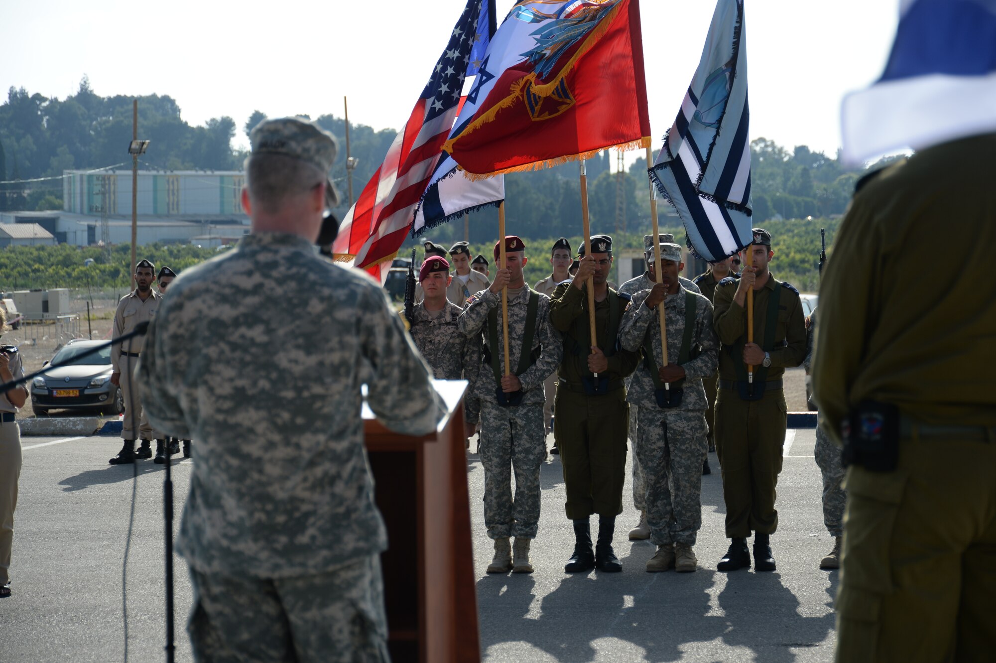 U.S. and Israeli color guard members bear their nations' and services' flags as U.S. Army Col. Greg Brady, commander of the 10th Army Air Missile Defense Command, left, speaks during the closing parade ceremony of the bilateral Juniper Cobra 14 defense exercise at Hatzor Air Base, Israel, May 22, 2014. JC14 is part of a long-standing agreement between U.S. European command and the Israeli Defense Force to hold bilateral training exercises on a regular basis in order to promote and sustain regional stability, and to ensure Israel’s qualitative military edge. (U.S. Air Force photo by Staff Sgt. Joe W. McFadden/Released)