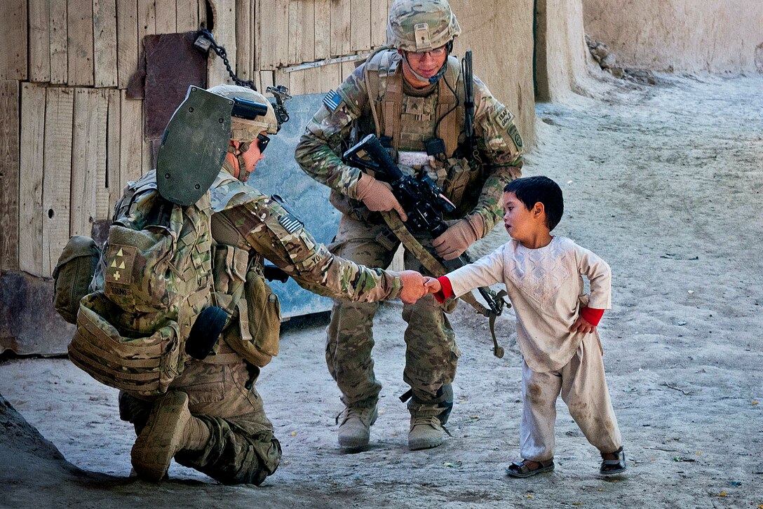 U.S. Army Spc. Harley Young greets an Afghan boy while on patrol in Muqor in Afghanistan's Ghazni province, June 27, 2012. Young is assigned to the 82nd Airborne Division's 1st Battalion, 504th Parachute Infantry Regiment, 1st Brigade Combat Team.  

