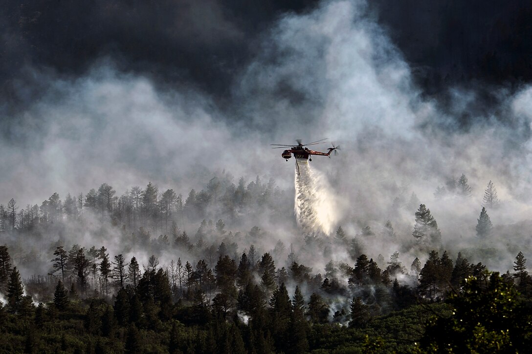A helicopter drops water on the wildfire burning in Waldo Canyon on the U.S. Air Force Academy outside of Colorado Springs, Colo., June 27, 2012. The fires, which have burned more than 15,000 acres, began spreading to the southwestern corner of the academy, causing base officials to evacuate residents. Officials estimated that the fire had spread to about 10 acres of land belonging to the Academy.  
