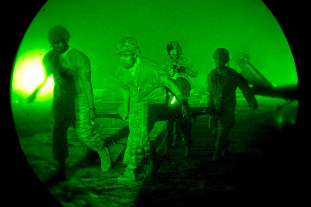 As seen through a night-vision device, Army and Navy medics transport a soldier with simulated injuries from a UH-60 Black Hawk helicopter to a field hospital as part of a medical evacuation scenario during Exercise Global Medic and Warrior Exercise on Fort Hunter Liggett, Calif., June 22, 2012.  
