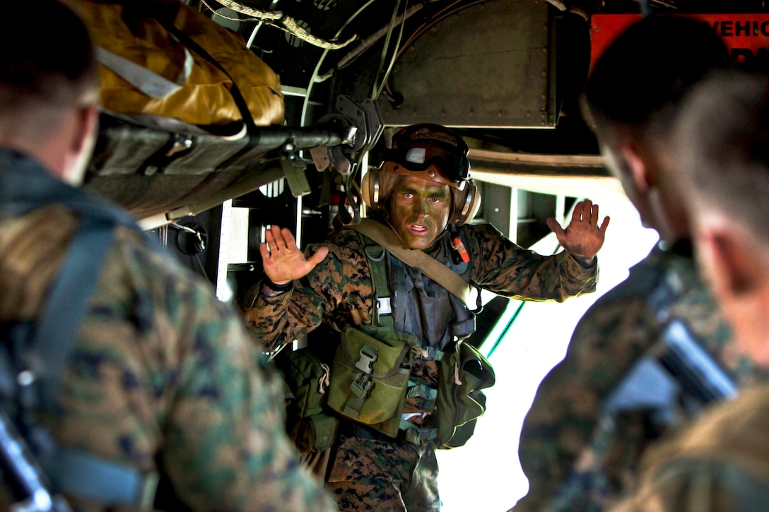 Marine Corps Gunnery Sgt. Shawn D. Decker signals his Marines to guide an inflatable raft out the back of a CH-53E Super Stallion helicopter into the water off the North Carolina coast as part of Operation Mailed Fist, June 18, 2012.  
