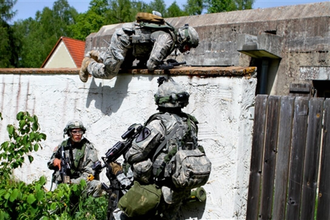U.S. soldiers jump over a wall while clearing a town during a partnered training exercise as part of Exercise Combined Resolve II at the Joint Multinational Readiness Center in Hohenfels, Germany, May 22, 2014. The soldiers are military policeman assigned to the 1st Cavalry Division's 72nd Brigade Military Police Detachment, 91st Brigade Engineer Battalion, 1st Brigade Combat Team. 