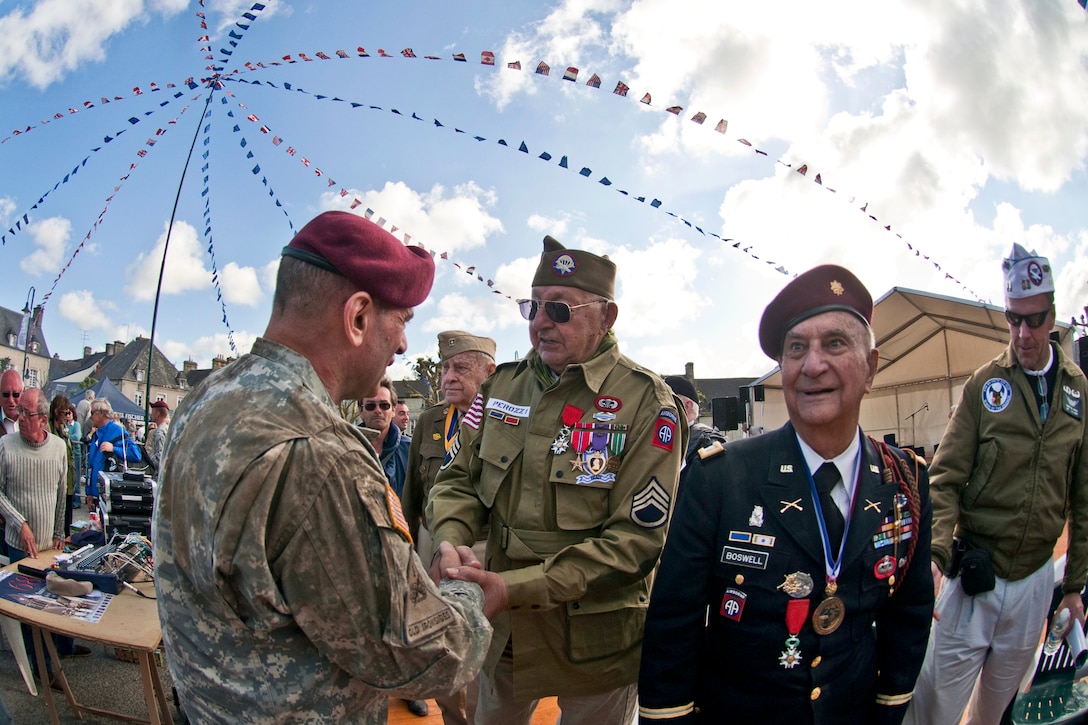 U.S. Army Maj. Gen. Jeffrey A. Jacobs, commanding general of the U.S. Army Civil Affiars & Psychological Operations Command, shakes hands with John Perozzi, a World War II and D-Day veteran who served with the 82nd Airborne Division, after a ceremony honoring him and other WWII veterans in Sainte-Mere-Eglise, France, June 3, 2012.  
