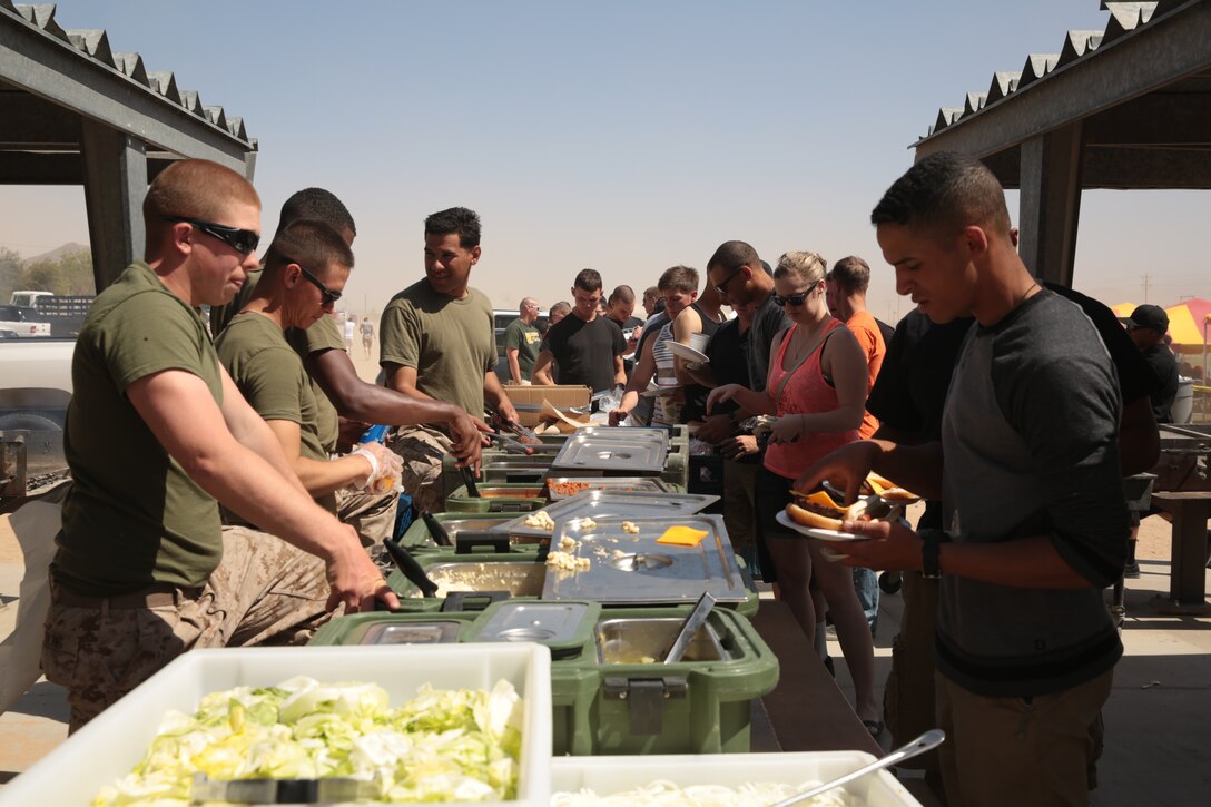 Food service specialists with 2nd Battalion 7th Marine Regiment, serve food to 2/7 Marines and their families during the unit's barracks bash hosted at Del Valle Field, May 10, 2014. The event was hosted by the unit to build camaraderie between the Marines who live in the barracks.