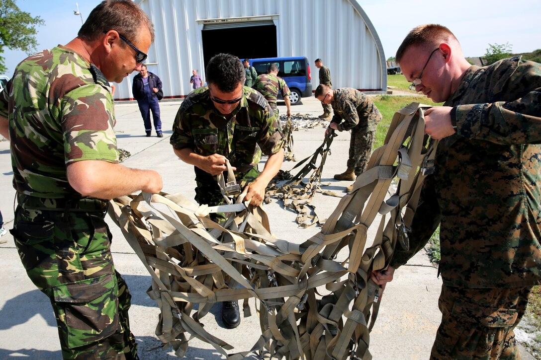 U.S. Marine Lance Cpl. Ryan Kinchen, a parachute rigger with Black Sea rotational Force 14, from 3rd Battalion, 8th Marine Regiment, examines a net with Romanian service members during a pallet building military-to-military engagement with on Mihail Kogalniceanu Air Base, May 28, 2014. The Marines and Romanians worked together, exchanging pallet-building techniques, different equipment and aircraft loading procedures during the military-to military-engagement in order to learn effective tactics from each other and increase interoperability between the two nations’ embarking units. 