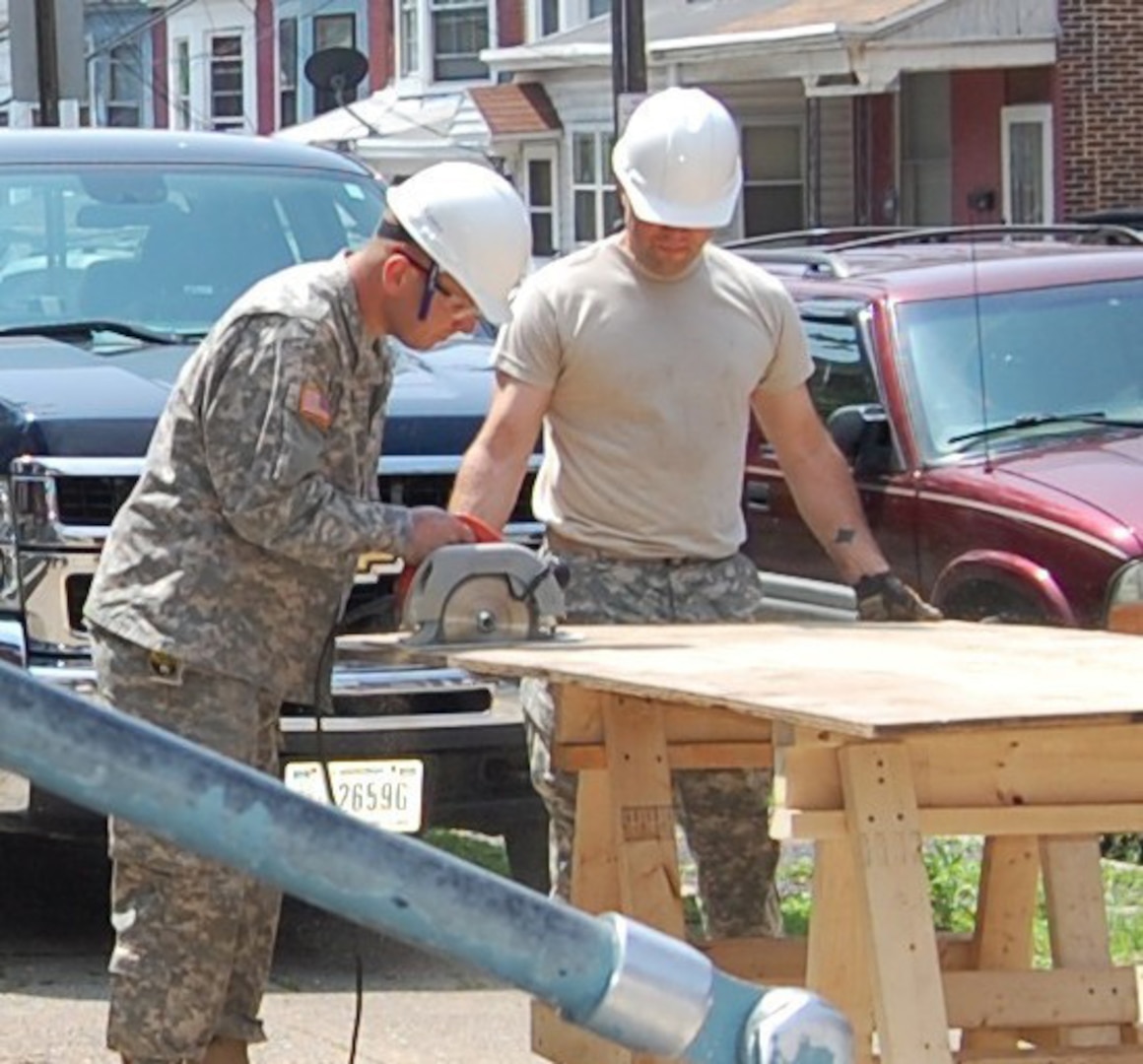 First Lt. Chad Korrel, Pennsylvania Army National Guard Medical Detachment, and Sgt. Derek Kessler, 2nd Battalion, 112th Infantry Regiment, 56th Stryker Brigade, 28th Infantry Division, cut boards to place over the windows and doors of condemned buildings in Harrisburg, Pa. The project was intended to secure the structures from vandals and drug abusers.