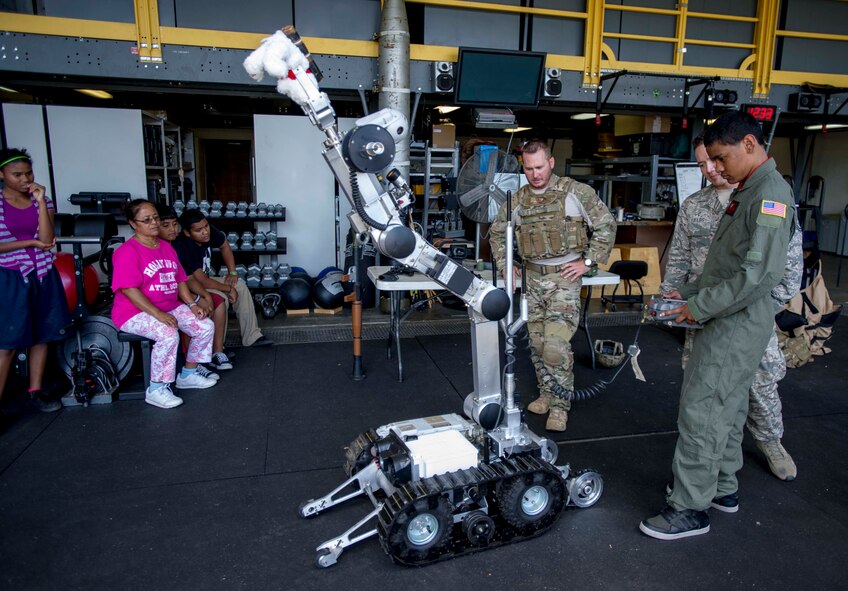 Kirby Balinski, a teenager battling Hodgkin’s Lymphoma, picks up a teddy bear during a demonstration of the Air Force medium sized robot at the 647th Civil Engineer Squadron Explosive Ordnance Disposal Flight facility on Joint Base Pearl Harbor-Hickam, Hawaii, May 29, 2014. Kirby was visiting the facility as part of the 15th Wing Pilot For a day Program, and was chosen to be a participant after being diagnosed with Hodgkin’s Lymphoma in October. (U.S. Air Force photo/Tech. Sgt. Terri Paden)