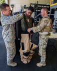 Master Sgt. David Fields, 647th Civil Engineer Squadron Explosive Ordnance Disposal Flight superintendent, left, and Tech. Sgt. Joshua Daley, 647th Civil Engineer Squadron Explosive Ordnance Disposal Flight craftsman, right, assist Kirby Balinski, a teenager battling Hodgkin’s Lymphoma, with putting on the bomb suit as part of the Pilot For a Day program at Joint Base Pearl Harbor-Hickam, Hawaii, May 29, 2014. (U.S. Air Force photo/Tech. Sgt. Terri Paden)
