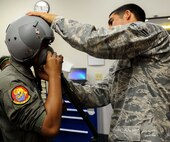 Airman 1st Class Eloy Ornelas, 15th Operations Support Squadron Aircrew Flight Equipment technician, assists Kirby Balinski, a teenager battling Hodgkin’s Lymphoma, with donning an oxygen mask as part of the Pilot For a Day program at Joint Base Pearl Harbor-Hickam, Hawaii, May 29, 2014. Kirby was chosen to participate in the Pilot For a Day program after being diagnosed with Hodgkin’s Lymphoma in October. (U.S. Air Force photo/Tech. Sgt. Terri Paden)