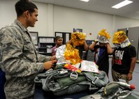 Airman 1st Class Eloy Ornelas, 15th Operations Support Squadron Aircrew Flight Equipment technician, shows Kirby Balinski, center flight suit, and his family members the proper way to don an emergency passenger oxygen system as part of the Pilot For a Day program at Joint Base Pearl Harbor-Hickam, Hawaii, May 29, 2014. Kirby was chosen to participate in the Pilot For a Day program after being diagnosed with Hodgkin’s Lymphoma in October. (U.S. Air Force photo/Tech. Sgt. Terri Paden)