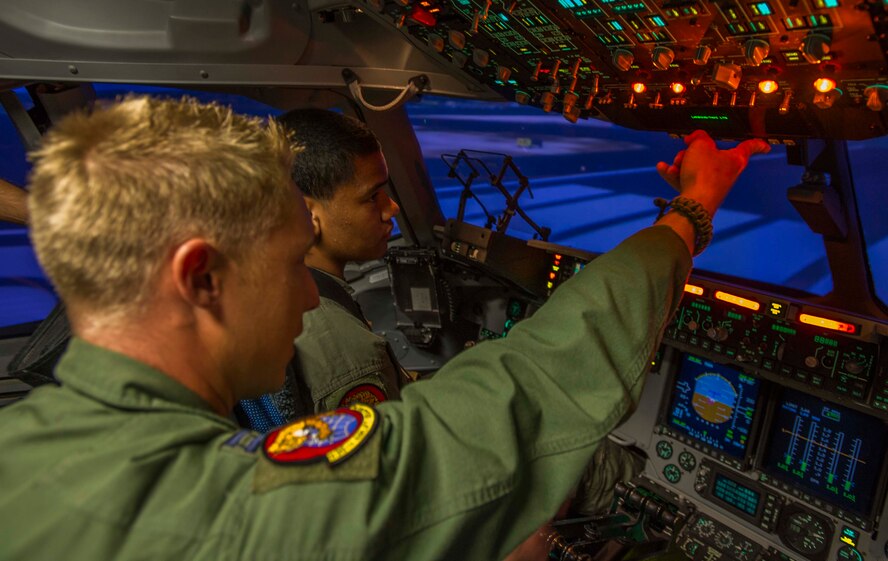 Kirby Balinski, a teenager battling Hodgkin’s Lymphoma, looks on as Capt. Damion Liu, a pilot in the 535th Airlift Squadron, explains how the C-17 Globemaster III simulator works as part of the Pilot For a Day program at Joint Base Pearl Harbor-Hickam, Hawaii, May 29, 2014. Hodgkin’s Lymphoma is a cancer of the lymphatic system, which compromises your body’s ability to fight infection. (U.S. Air Force photo/Tech. Sgt. Terri Paden)