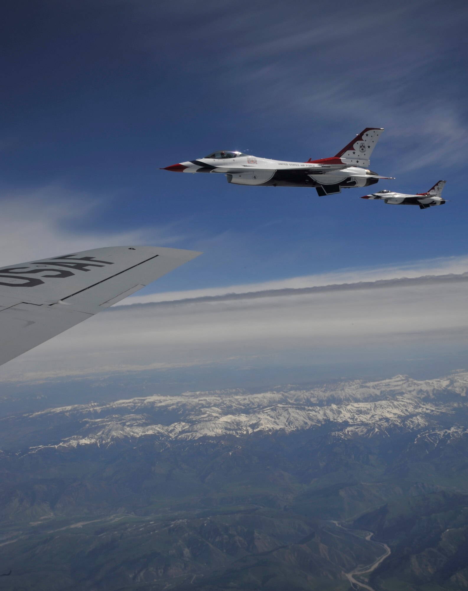 Members of the U.S. Air Force Thunderbird team fly along next to a KC-135 Stratotanker while being escorted to Fairchild Air Force Base, Wash., May 29, 2014. Members of Fairchild's local media agencies were able to fly on this escort and air refueling mission as an orientation flight to prepare communities for the upcoming air show. The Thunderbirds perform precision aerial maneuvers demonstrating the capabilities of Air Force high performance aircraft to people throughout the world. (U.S. Air Force photo by Senior Airman Mary O'Dell/Released)