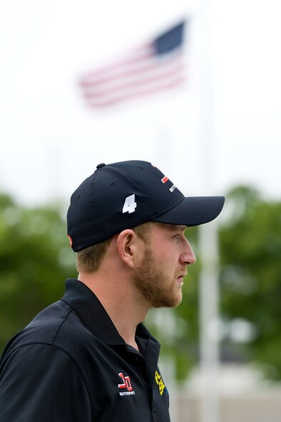A U.S. Flag in the Memorial Circle at the Charles C. Carson Center for Mortuary Affairs waves in the background as Jeffrey Earnhardt, NASCAR Nationwide Series driver of the JD Motorsports No. 4 Chevrolet Camaro, finishes his orientation of Air Force Mortuary Affairs Operations, Dover Air Force Base, Del., May 28, 2014.  Earnhardt received briefings and met with personnel at AFMAO and the Armed Forces Medical Examiner System while in Dover for race week. (U.S. Air Force photo/Roland Balik)