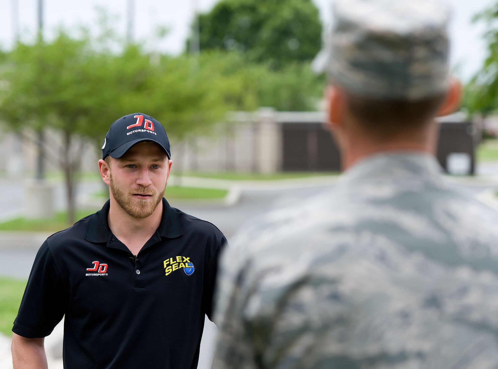 Tech. Sgt. Brett Gosney, 436th Airlift Wing public affairs broadcaster, interviews Jeffrey Earnhardt, NASCAR Nationwide Series driver of the JD Motorsports No. 4 Chevrolet Camaro, May 28, 2014,in front of the Charles C. Carson Center for Mortuary Affairs, Dover Air Force Base, Del. Earnhardt  received an orientation of Air Force Mortuary Affairs Operations and the Armed Forces Medical Examiner System. (U.S. Air Force photo/Roland Balik)