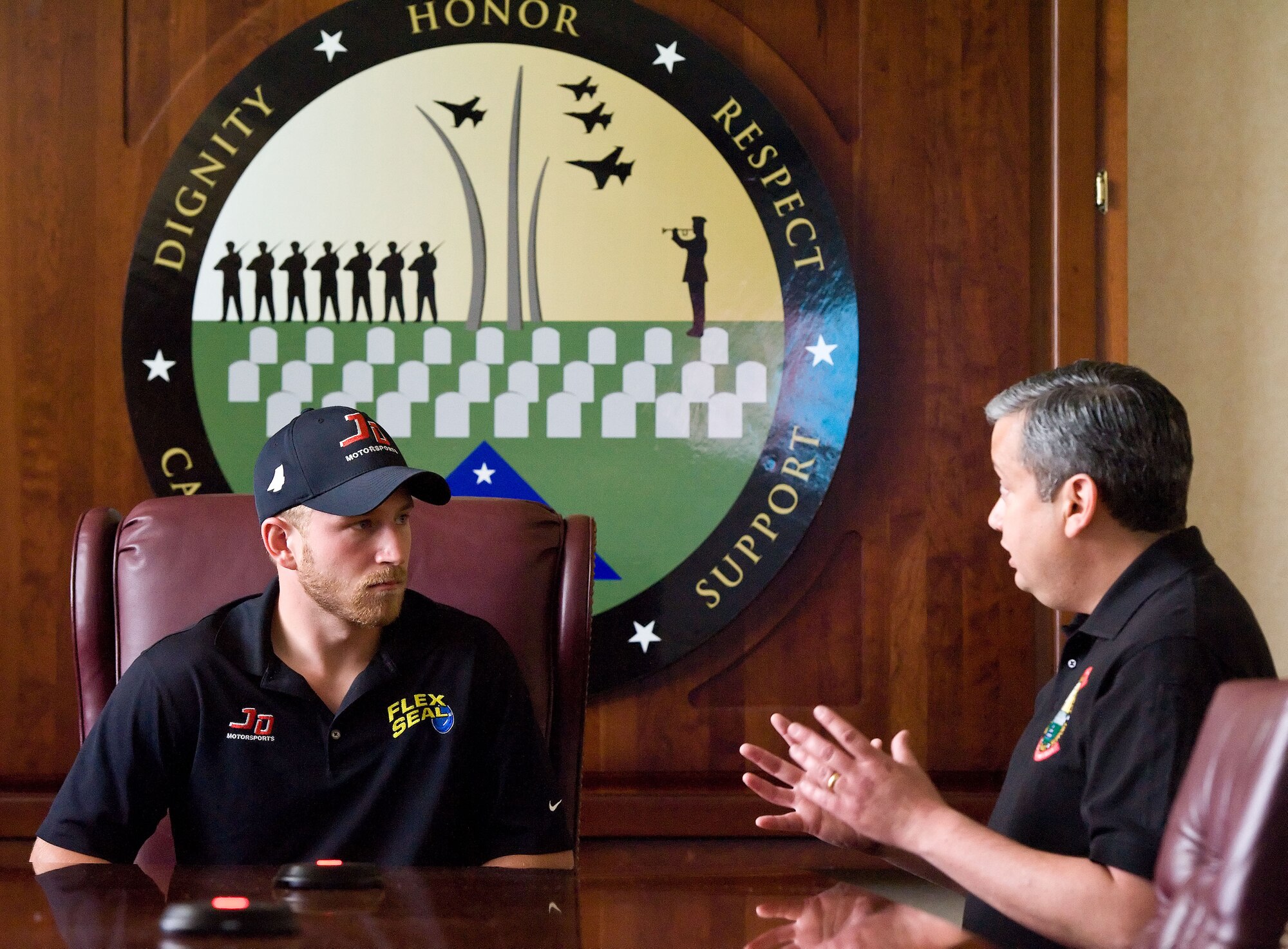 Jeffrey Earnhardt, left, NASCAR Nationwide Series driver of the JD Motorsports No. 4 Chevrolet Camaro, listens to Ruben Garza, Air Force Mortuary Affairs Operations mortuary specialist, May 28, 2014, at Dover Air Force Base, Del. Garza explained the role of the past conflicts mission. Garza's team works with families of Airmen whose remains are still unaccounted for. (U.S. Air Force photo/Roland Balik)