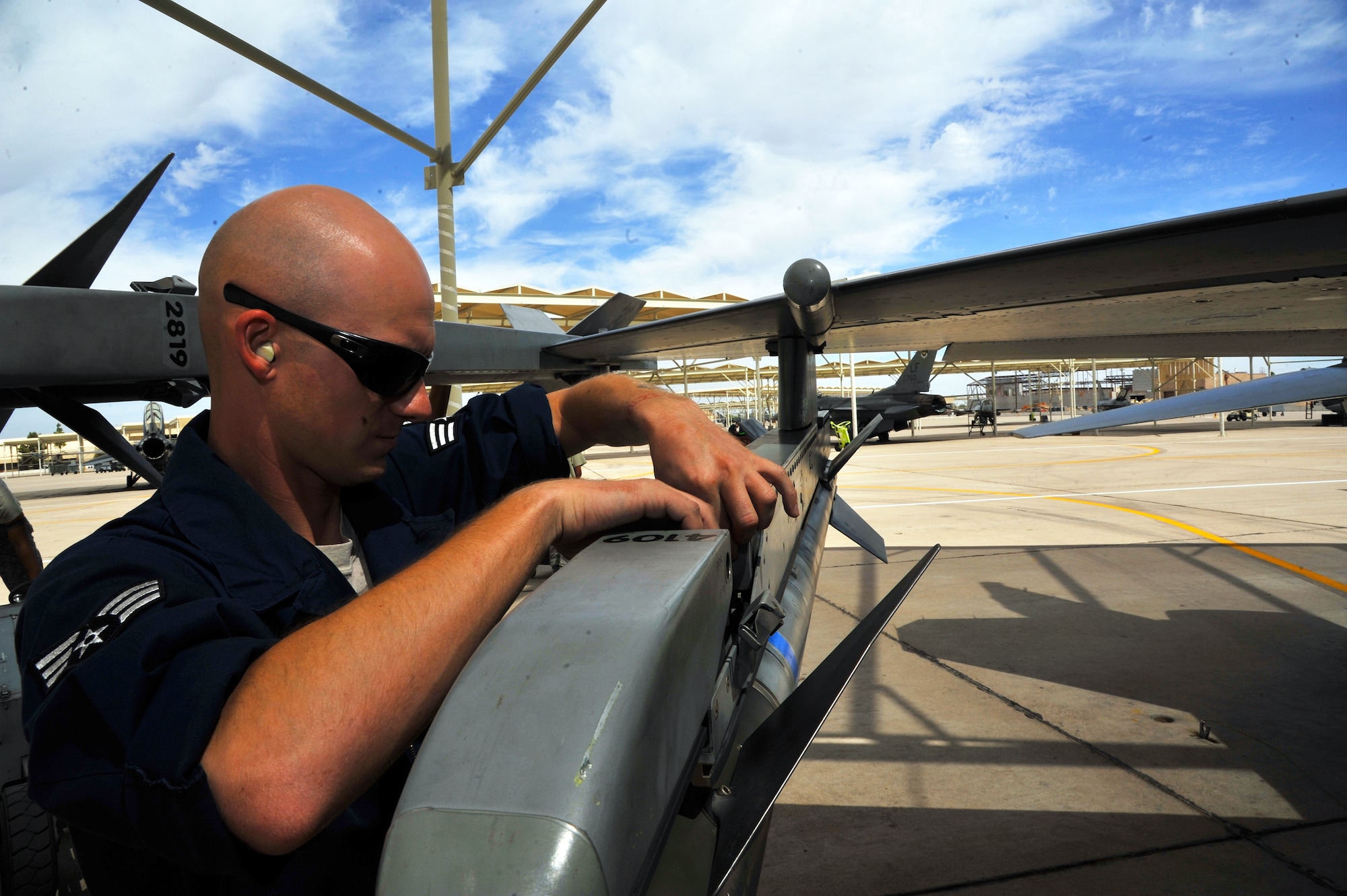 Senior Airman Charles Gros, 310th Aircraft Maintenance Unit aircraft armament systems technician, hooks up the umbilical cable from a missile to an F-16 Fighting Falcon April 15 at Luke Air Force Base. The umbilical cable transfers commands to arm and release the missile. (U.S. Air Force photo/Senior Airman Jason Colbert)