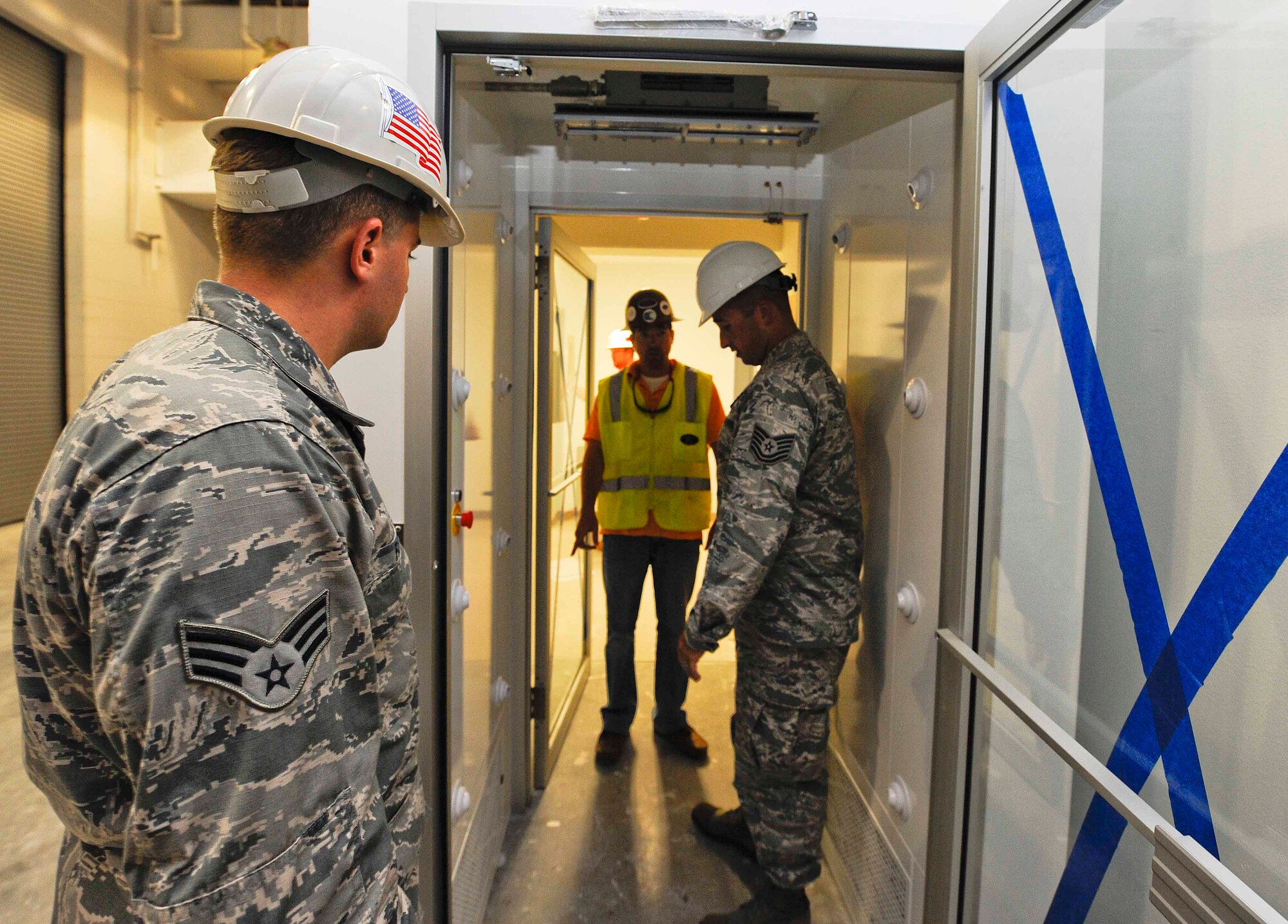 Senior Airman William Farr and Tech. Sgt Timothy Emeott, 1st Special Operations Contracting Squadron, contracting specialists, oversee construction and placement of an air shower in the 1st Special Operations Equipment Maintenance Squadron at Hurlburt Field, Fla., May 20, 2014. The air shower will decontaminate Airmen’s uniforms after they’ve worked with paint that contains health hazards. (U.S. Air Force photo/Airman 1st Class Andrea Posey)