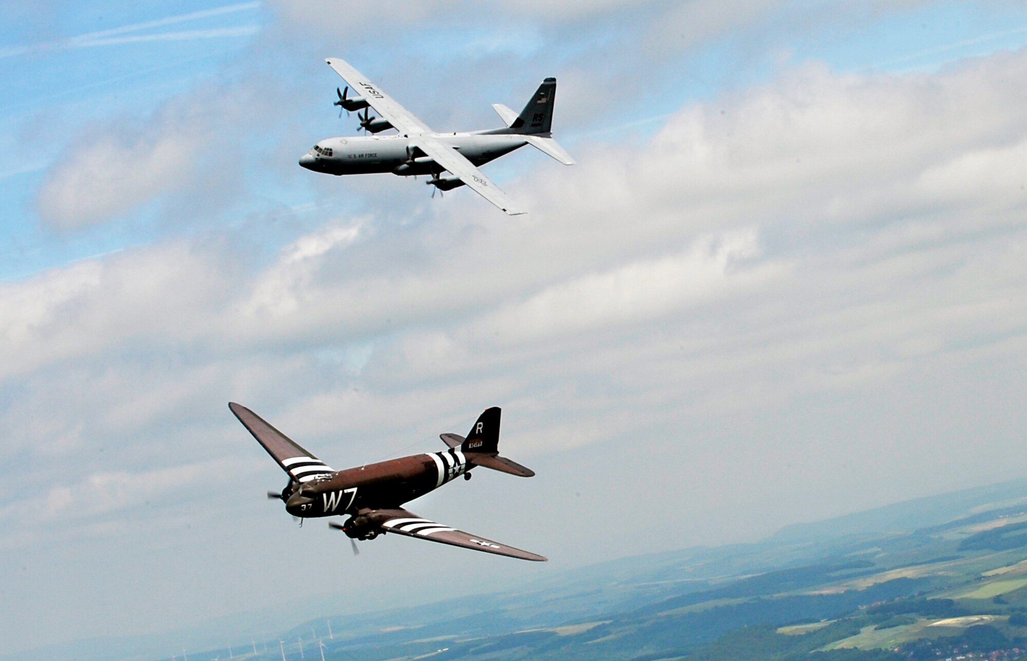 A Douglas C-47 Skytrain, known as Whiskey 7, flies alongside a C-130J Super Hercules from the 37th Airlift Squadron over Germany, May 30, 2014. The C-47 came to Ramstein for a week to participate in base activities with its legacy unit, the 37th Airlift Squadron, before returning to Normandy to recreate its role and drop paratroopers over the original drop zone in Sainte-Mere Eglise, France. (U.S. Air Force photo/Staff Sgt. Sara Keller)