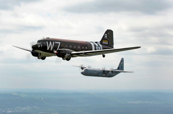 A Douglas C-47 Skytrain, known as Whiskey 7, flies alongside a C-130J Super Hercules from the 37th Airlift Squadron over Germany, May 30, 2014. The C-47 came to Ramstein for a week to participate in base activities with its legacy unit, the 37th Airlift Squadron, before returning to Normandy to recreate its role and drop paratroopers over the original drop zone in Sainte-Mere Eglise, France. (U.S. Air Force photo/Staff Sgt. Sara Keller)