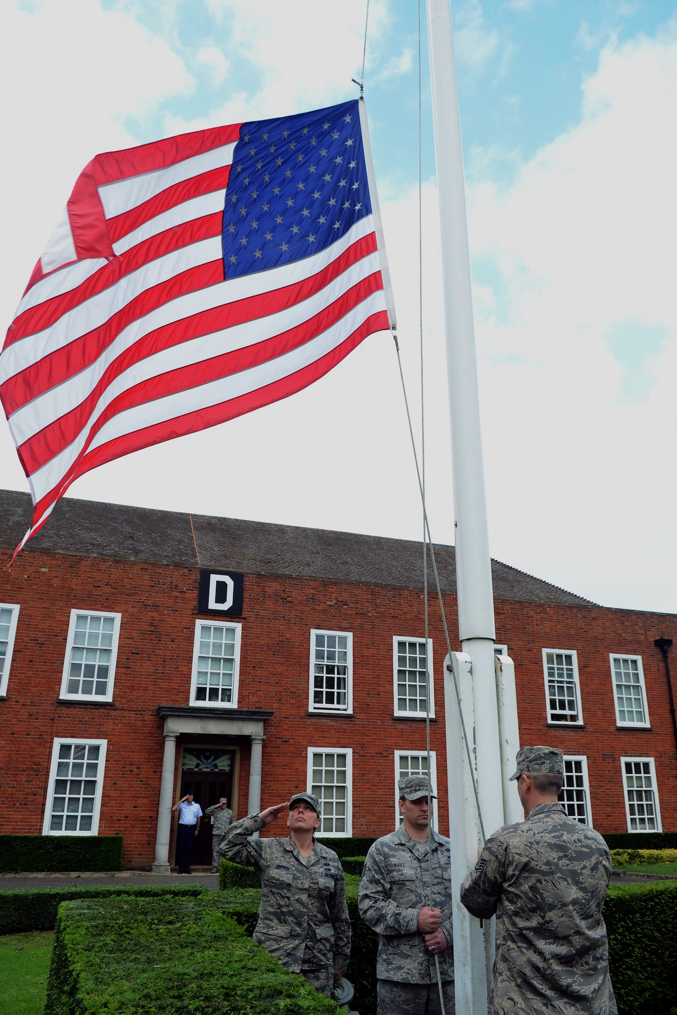Members of a Team Mildenhall flag detail lowers the U.S. flag during a retreat ceremony May 30, 2014, on RAF Mildenhall, England. A retreat ceremony, in which the flag detail retires the U.S. flag and Royal Air Force ensign, is scheduled to take place the last Friday of every month. (U.S. Air Force photo/Airman 1st Class Kyla Gifford/Released)