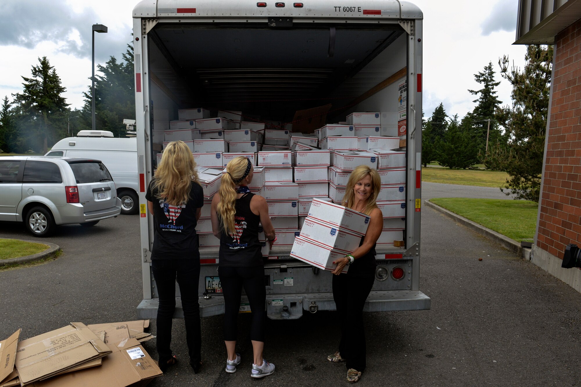 Suni Chabrow, Douglas J. Green Memorial Foundation founder, and two members of her organization offload the first care packages from a truck to the JBLM USO Northwest Shali center, May 29, 2014, at Joint Base Lewis-McChord. This will be the first time the group has not had to pay expensive shipping costs to send care packages to troops stationed overseas. (U.S. Air Force photo/Staff Sgt. Russ Jackson)