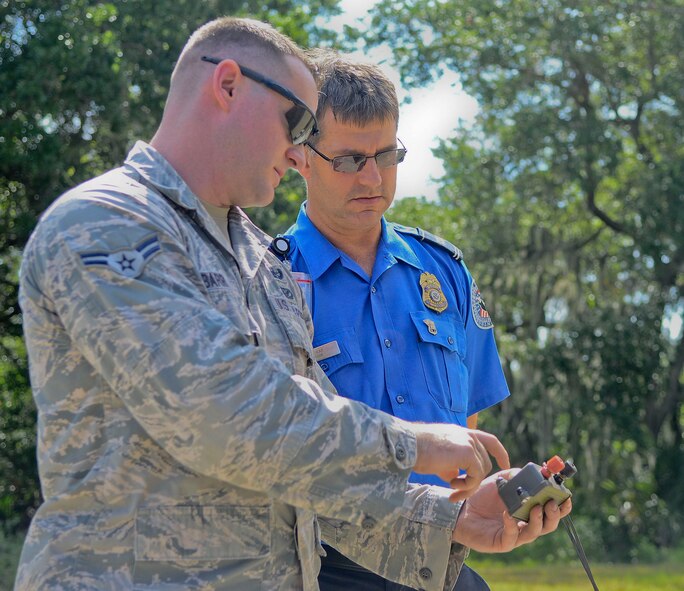 Airman 1st Class John J. Barr IV, 6th Civil Engineer Squadron explosive ordnance disposal technician, demonstrates proper detonation protocol with Patrick Laskey, Transportation Security Administration officer, at the EOD range May 28, 2014, at MacDill Air Force Base, Florida. Thirty-one TSA personnel came out to MacDill for a joint training to observe the destructive capability of real explosives. (U.S. Air Force photo/Airman 1st Class Ned T. Johnston)