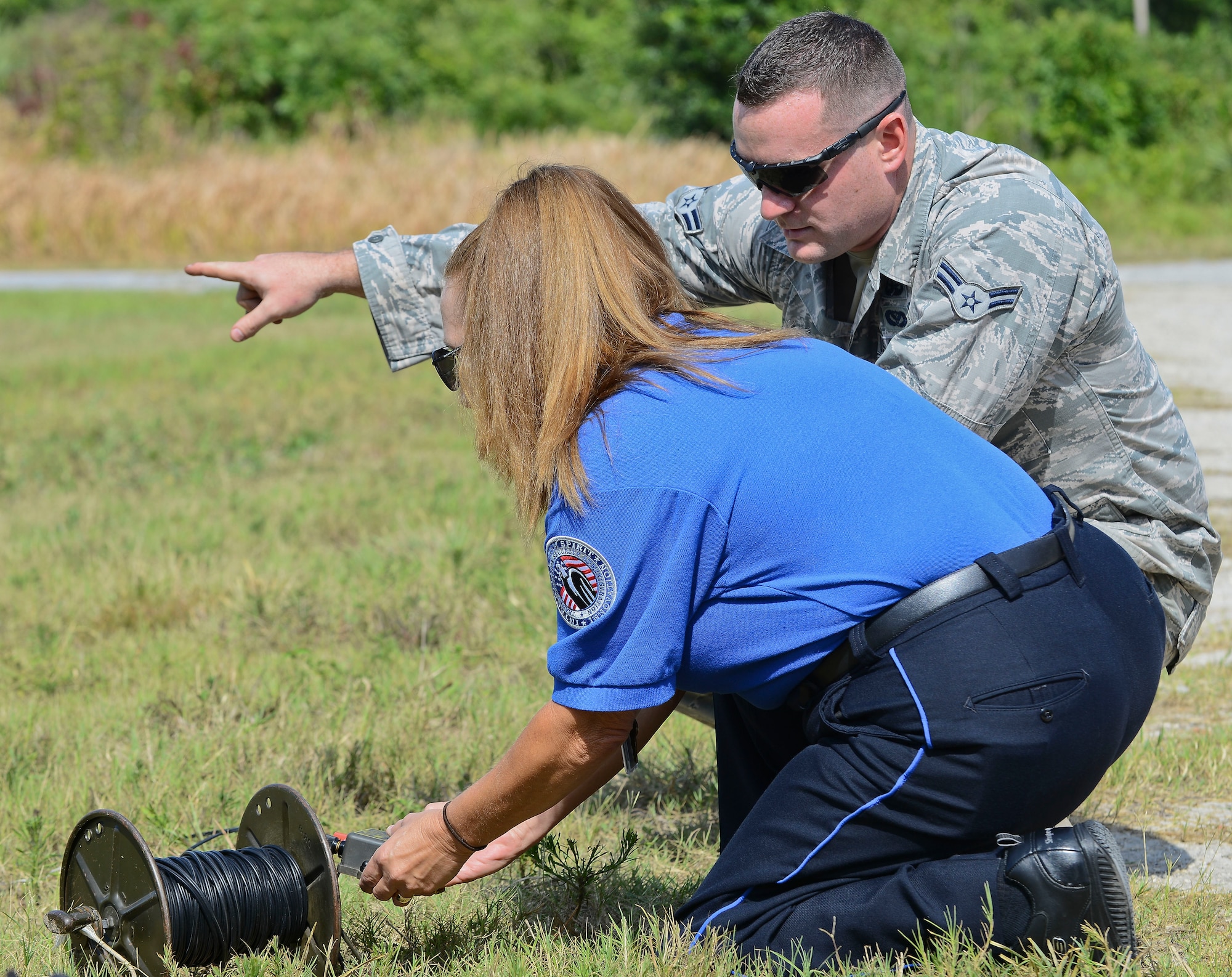Airman 1st Class John J. Barr IV, 6th Civil Engineer Squadron explosive ordnance disposal technician, demonstrates proper detonation protocol with Michele Rudd, Transportation Security Administration officer, at the EOD range May 28, 2014, at MacDill Air Force Base, Fla. Barr was pointing to the area downrange where Rudd’s remote detonation would take place. (U.S. Air Force photo by Airman 1st Class Ned T. Johnston/Released)